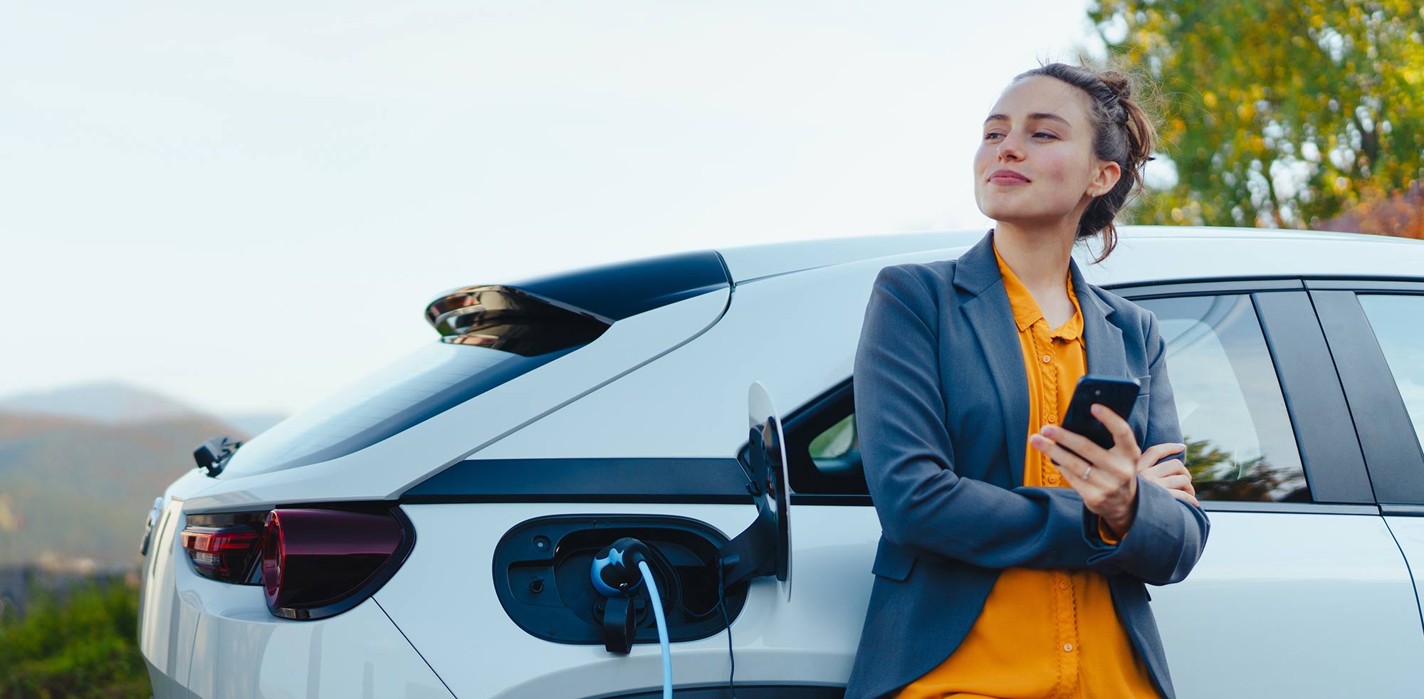 AvD Artikel - Frau steht an einer Ladesäule und lädt den Wagen auf.