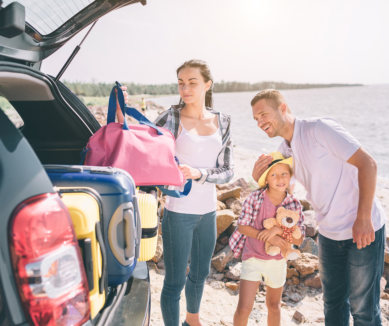 Eine Familie lädt das Auto mit Gepäck für den Sommerurlaub Eine Familie lädt das Auto mit Gepäck für den Sommerurlaub