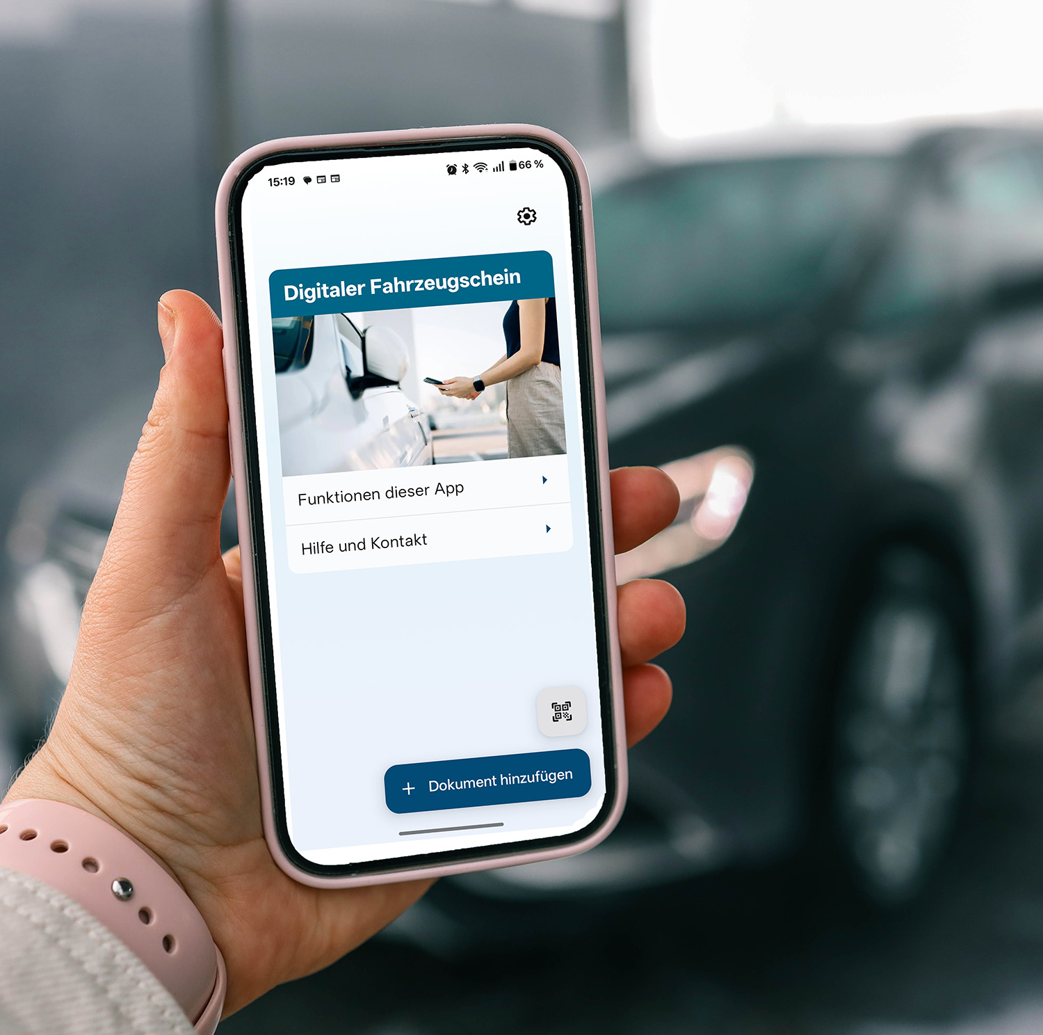 Ansicht der i-Kfz-App auf einem Smartphone vor einem im Hintergrund stehenden Auto