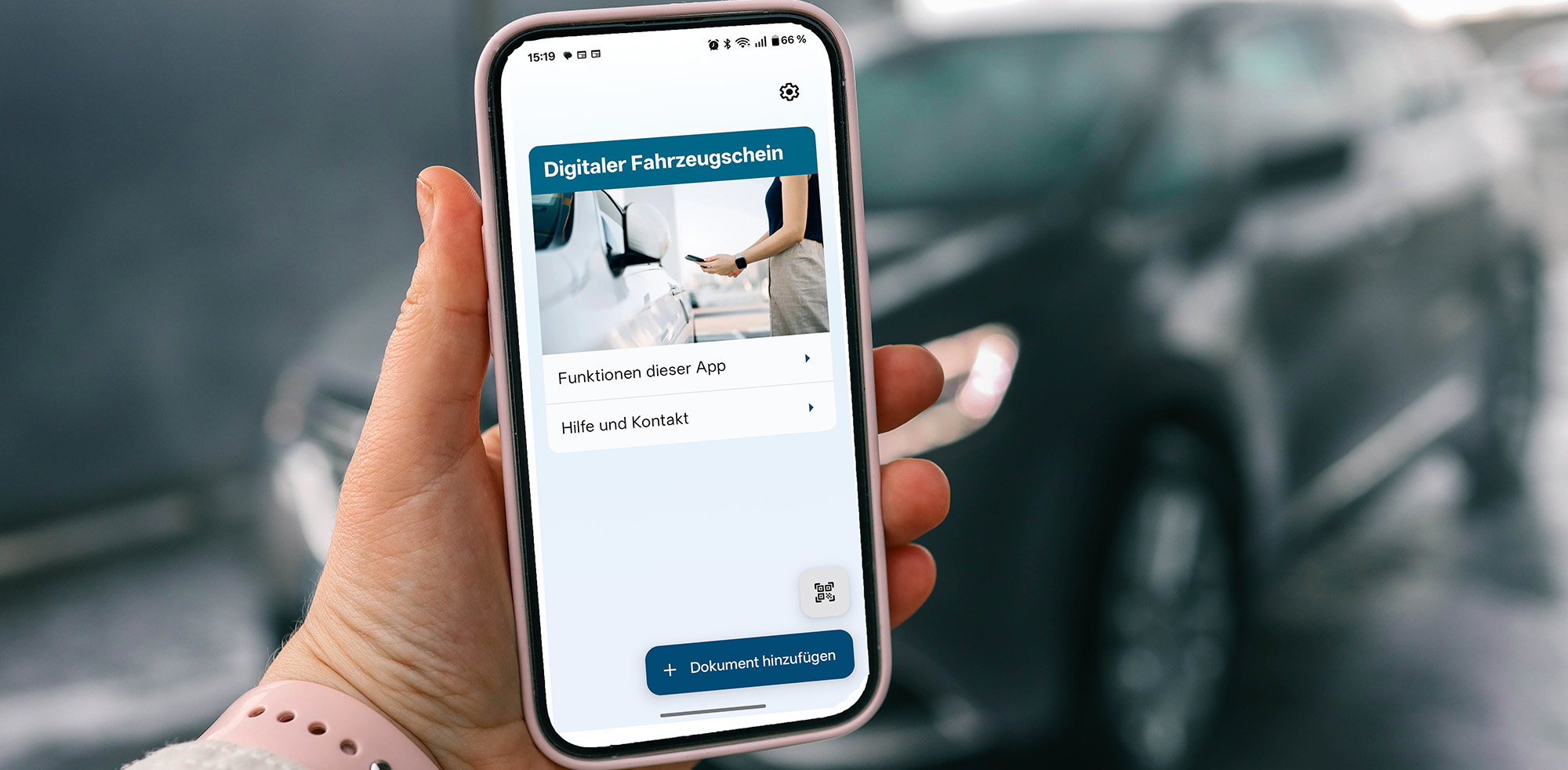 Ansicht der i-Kfz-App auf einem Smartphone vor einem im Hintergrund stehenden Auto